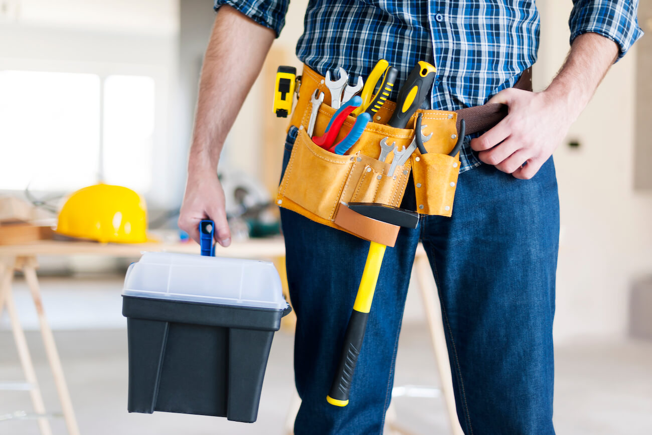 man holding tools in and wearing yellow belt