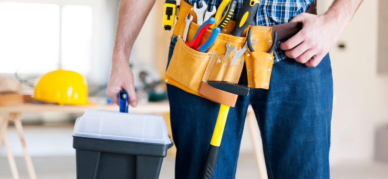 man holding tools in and wearing yellow belt